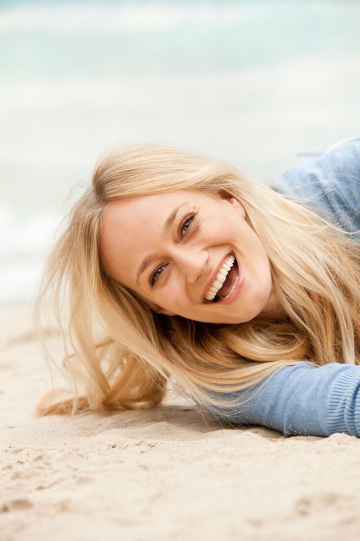 Close-up of happy blonde woman enjoying on the sand, laughing