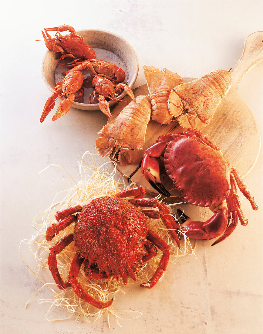 Various crabs and shrimps on straw and wooden board