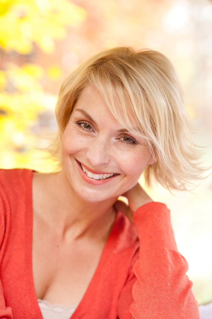 Portrait of pretty blonde woman with short hair wearing red sweater, smiling