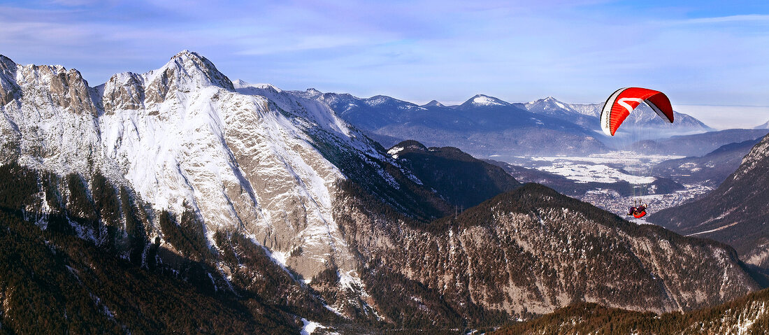 Man paragliding between snow mountains at Leutaschtal, North Tyrol, Italy