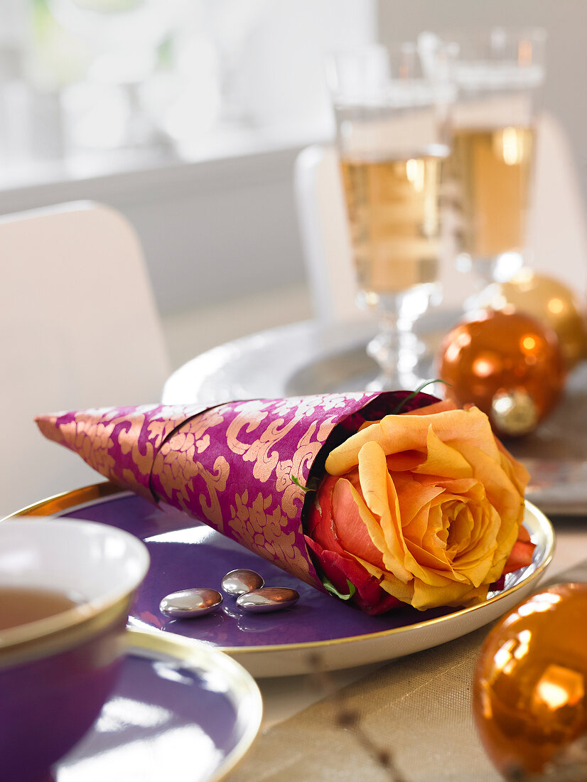 Close-up of rose wrapped in purple paper on plate