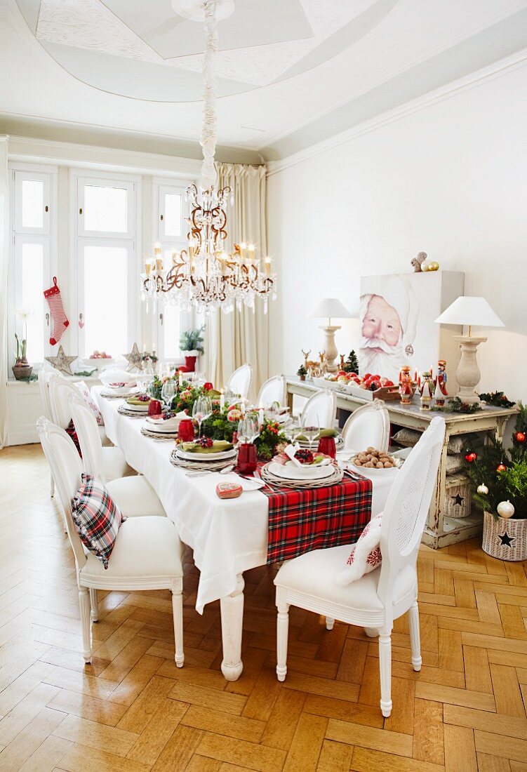A land-house style table laid for Christmas dinner with a tartan table runner
