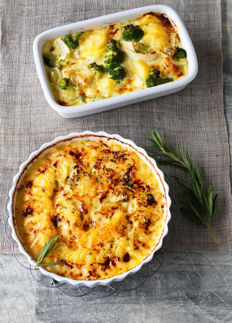 Vegetable casserole and potatoes au gratin with rosemary in baking tin