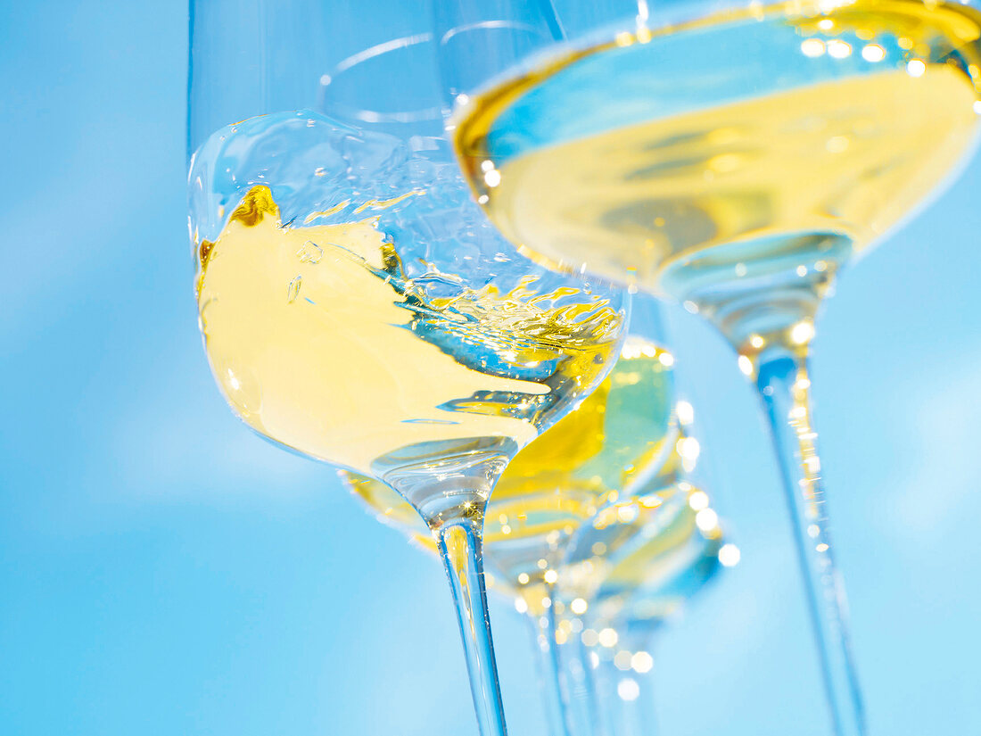 Close-up of white wine in swung glass on blue background