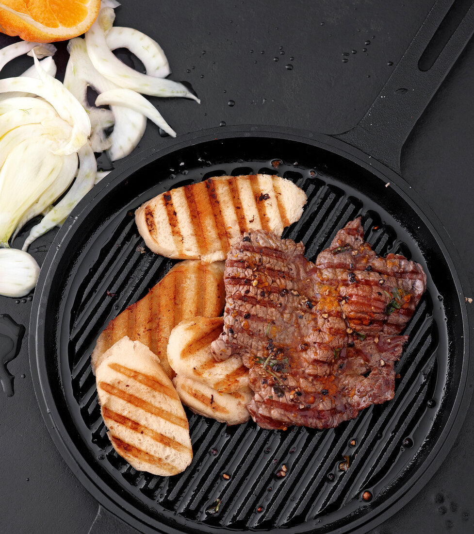 Close-up of steaks with orange and berry on frying pan