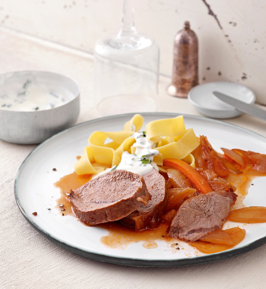 Glazed veal shoulder with onions and pasta on plate