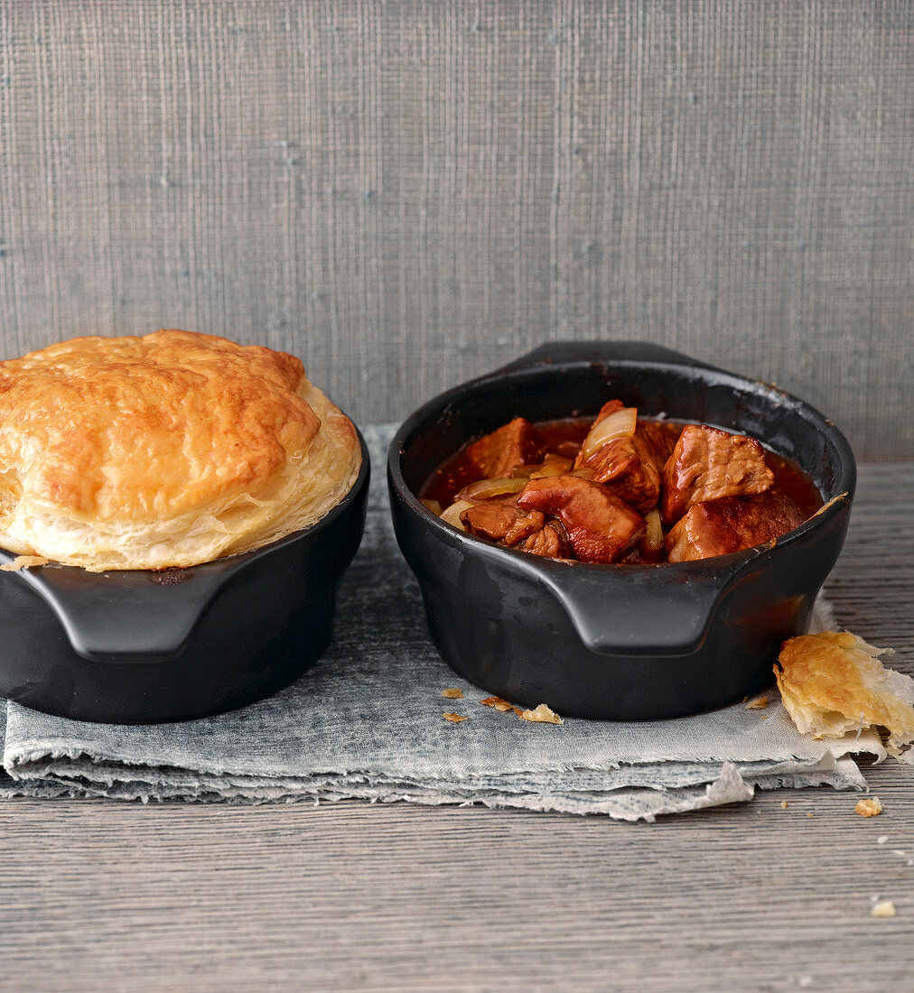 Stew with puff and pastry crust in woks