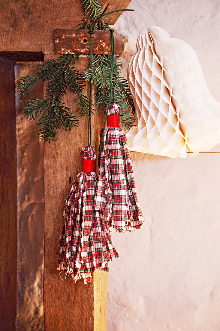 Plaid fabric tassels and fir leaves hanging on door