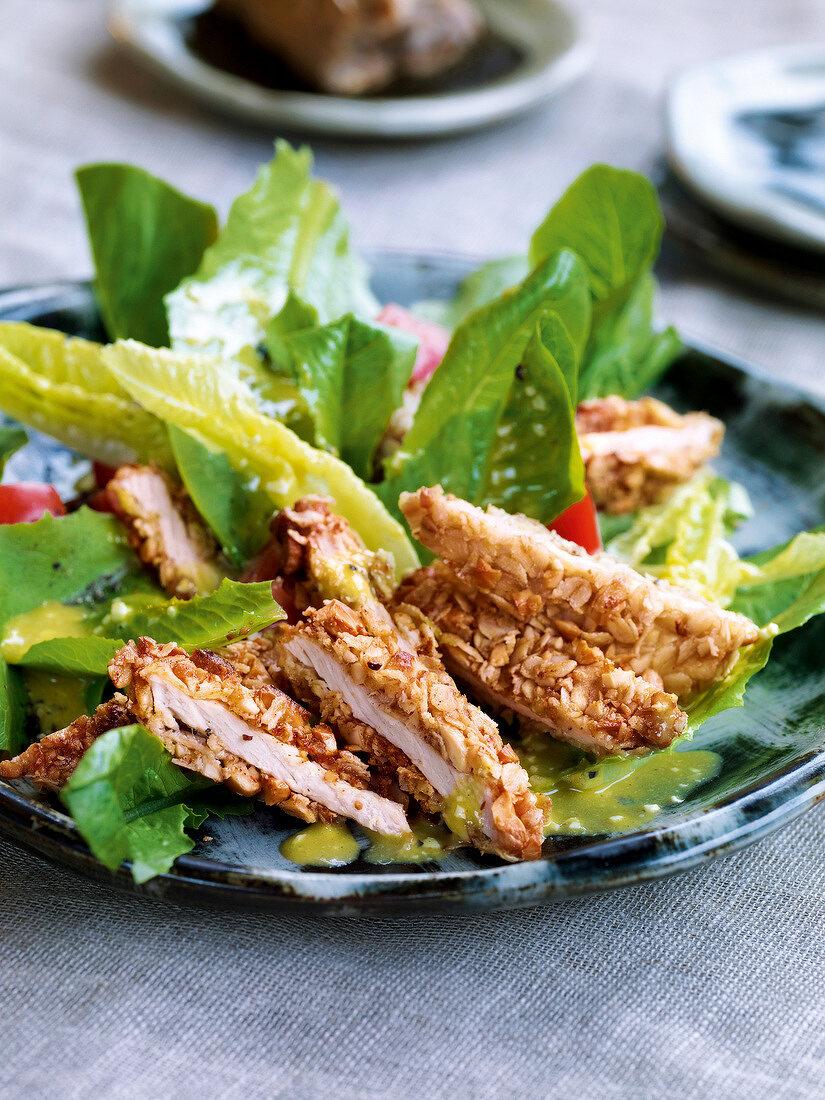 Caesar salad with pan fried crispy cutlets on plate