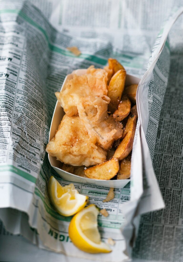 Fish and chips with lemon wrapped in newspaper