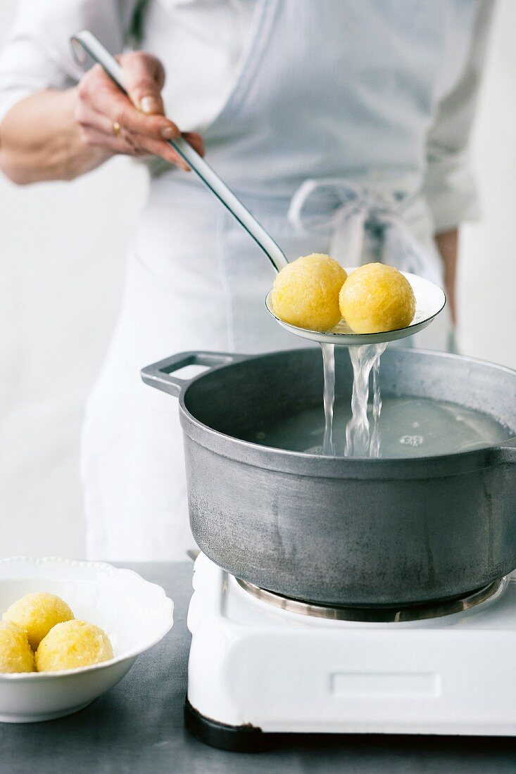 Potato dumplings being removed from a pan of boiling water