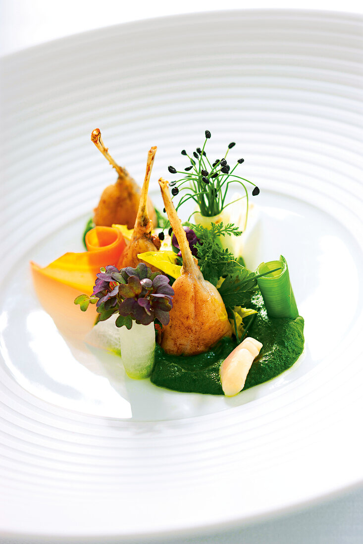 Vegetable with wild herbs and frog legs on plate
