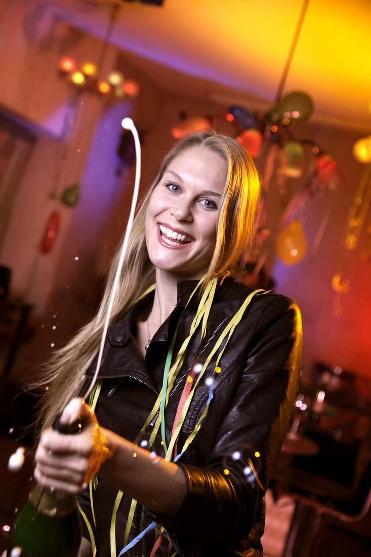 Portrait of happy woman wearing leather jacket celebrating New Year's with champagne