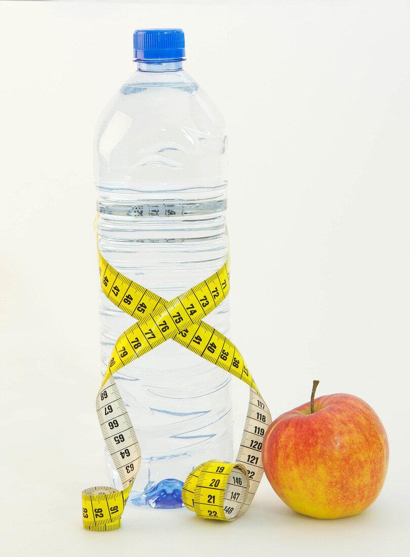 Symbolbild für Diät, Flasche Wasser mit Maßband und roter Apfel