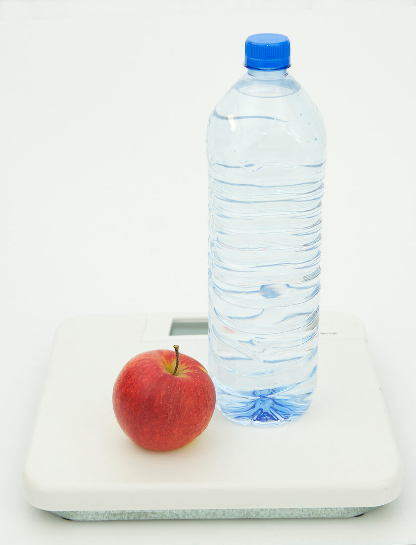 Symbolbild für Diät, Apfel und Flasche Wasser auf Waage