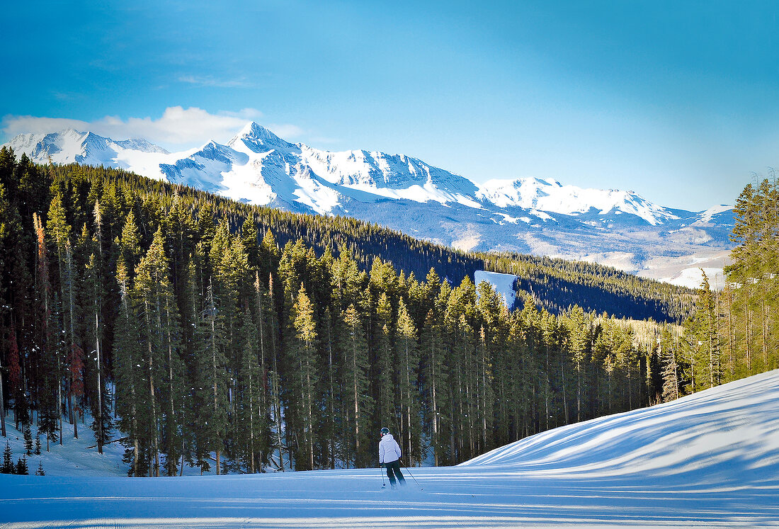 View of snow skier with Rocky Mountains overlooking, Colorado,