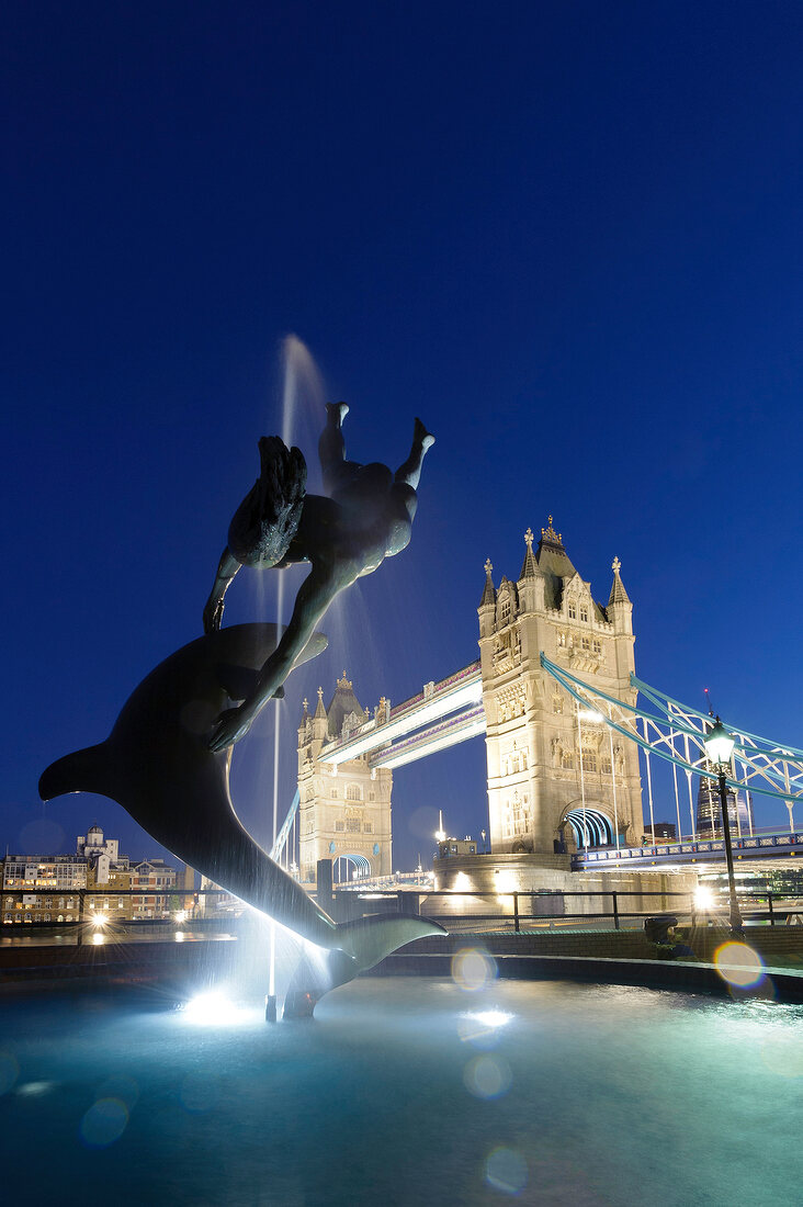 Sculpture of dolphin with girl and Tower Bridge in background at Southwark, London, UK