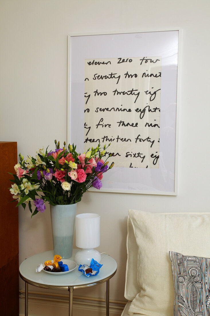 Table with flower vase and picture frame on wall