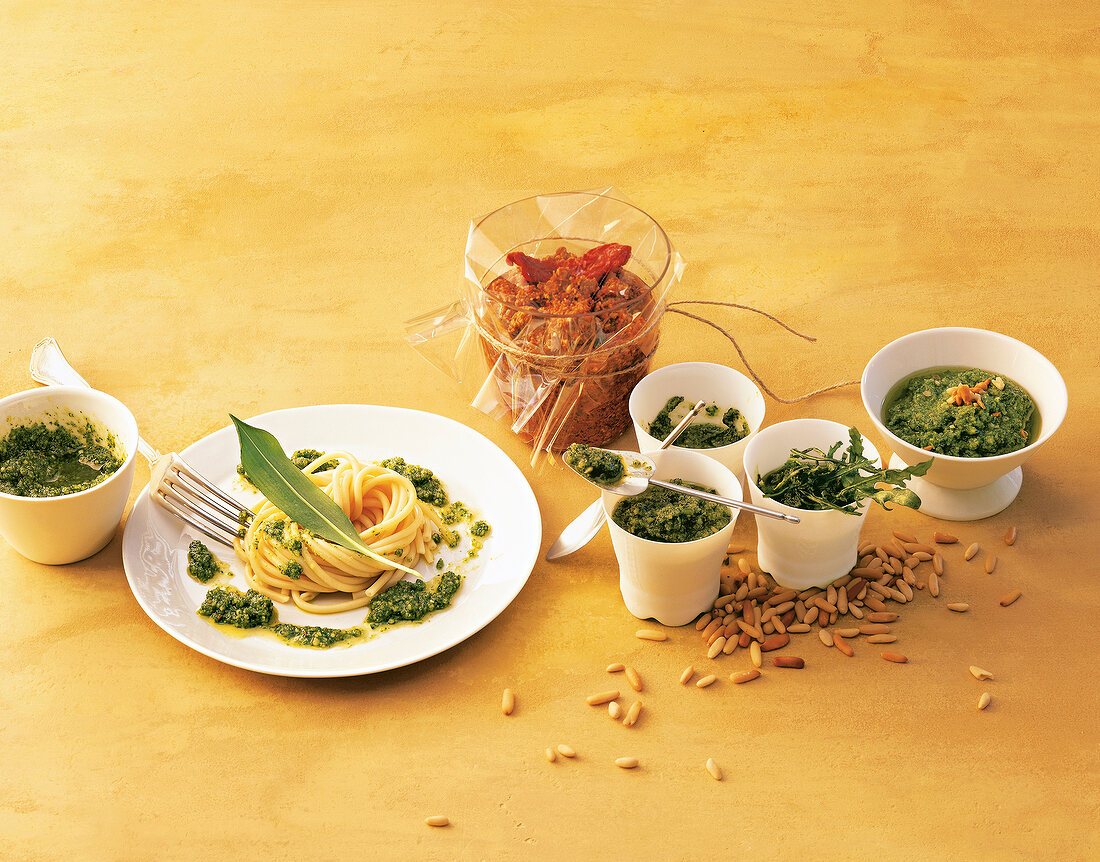 Bowls and glass of pesto with spaghetti on plate