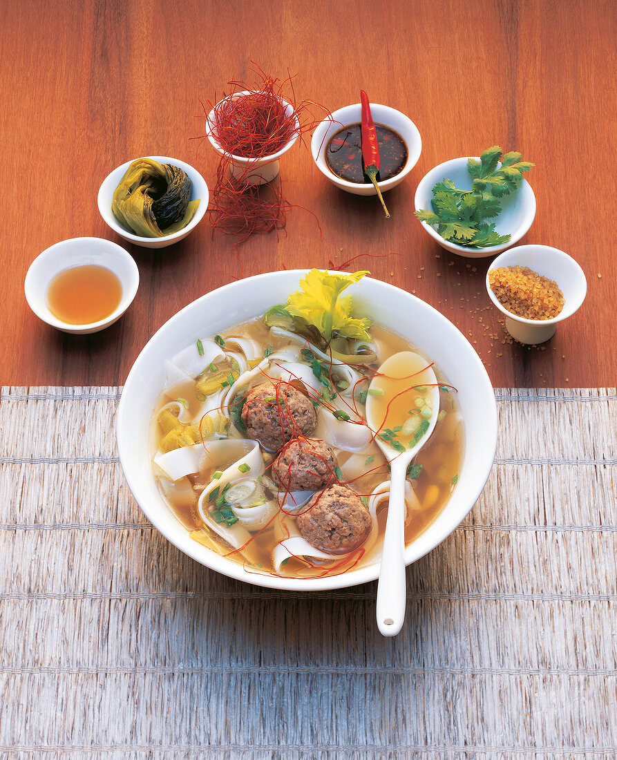 Thai soup with rice noodles and meatballs in bowl