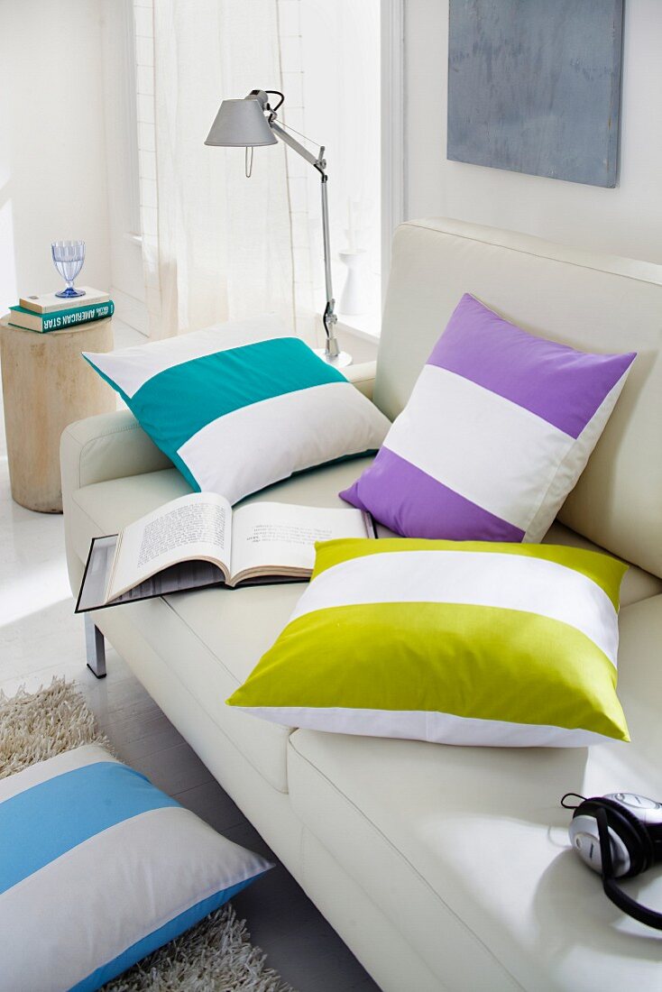 Scatter cushions with wide, brightly-coloured stripes on sofa