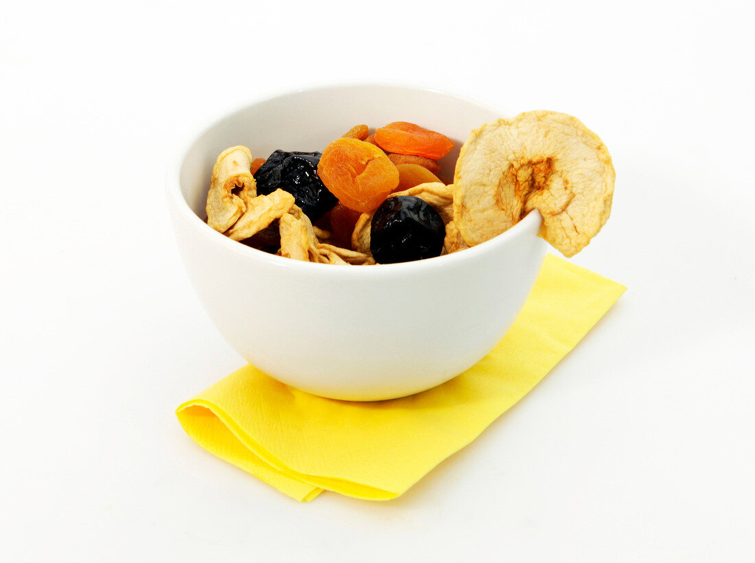 Bowl of various dried fruits on white background