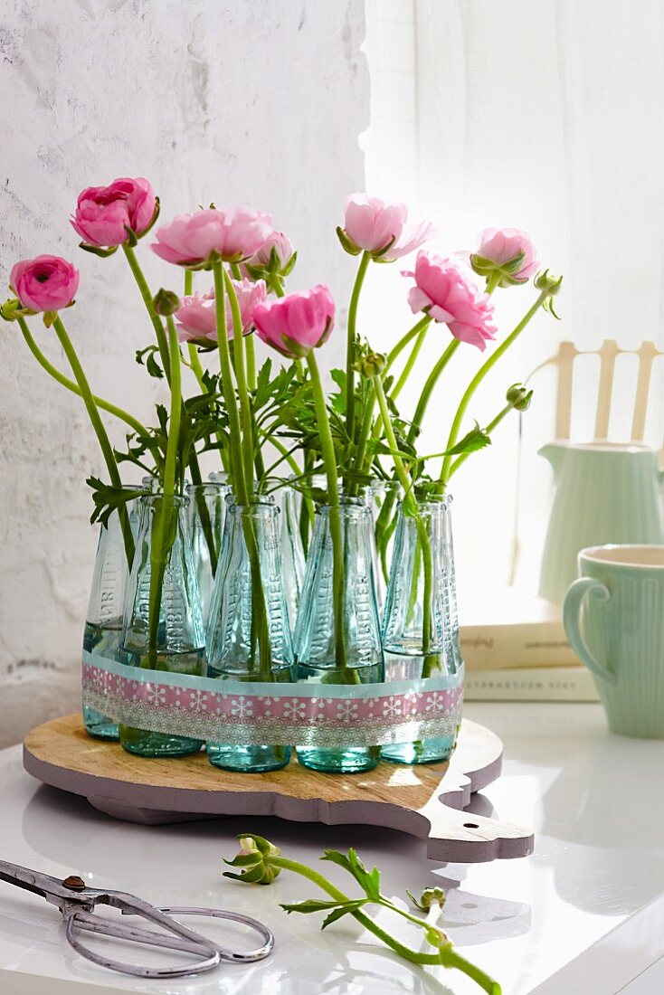 Ranunculus in several miniature bottles used as vases