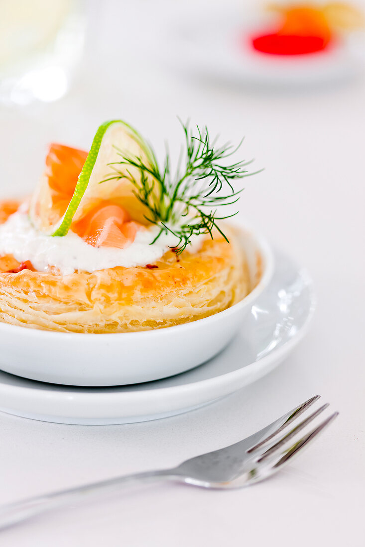 Close-up of puff pastry tart with salmon and dill on bowl