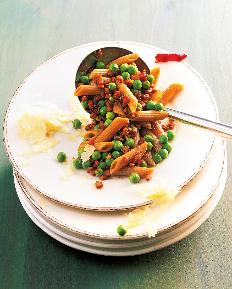 Penne rigate pasta with peas and prosciutto on plate