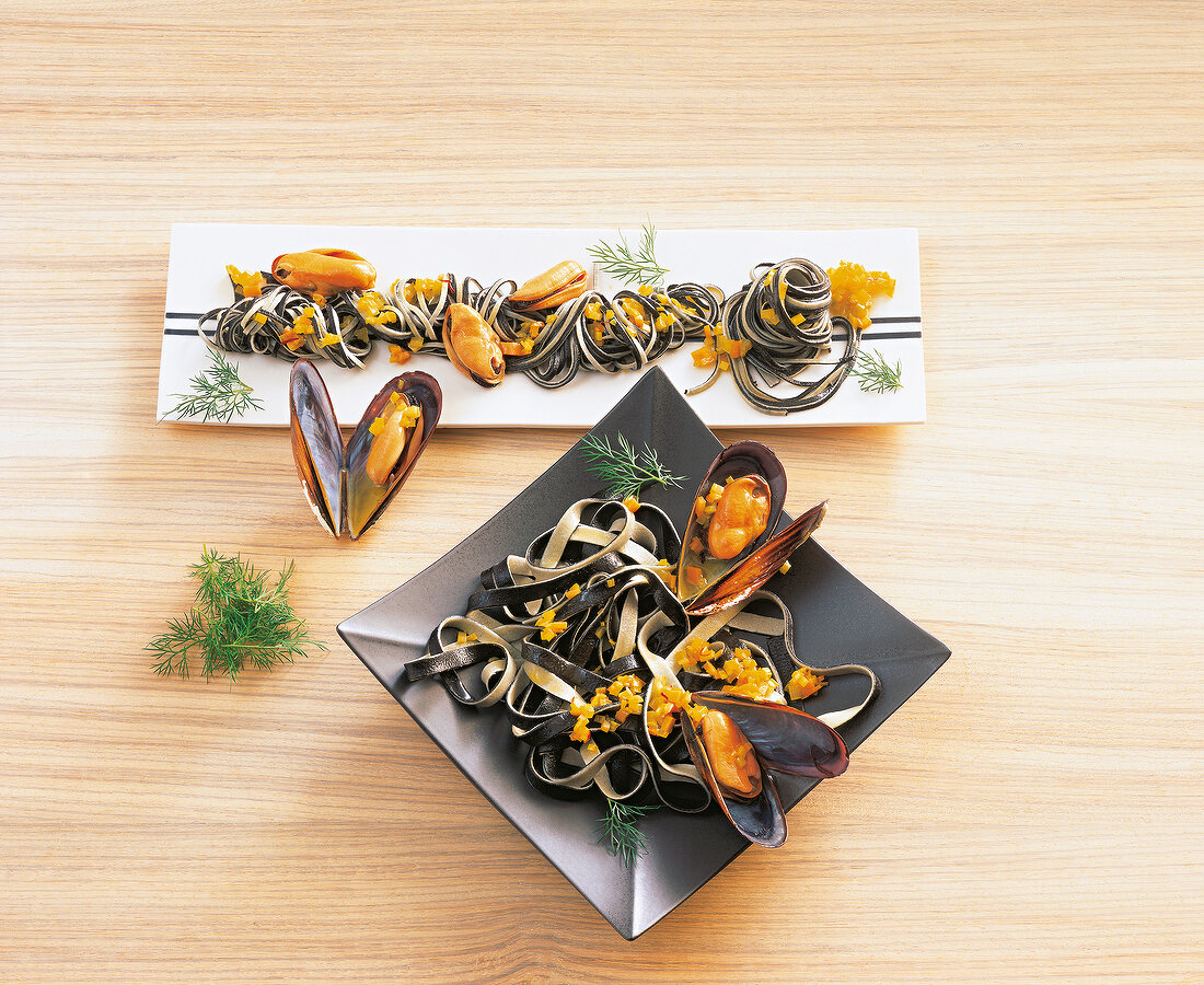 Black and white tagliatelle with mussels on plates