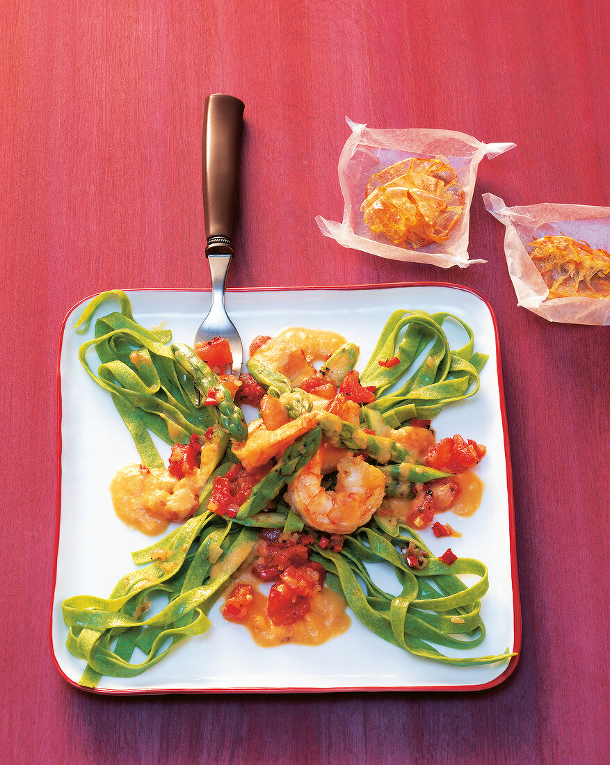 Green tagliatelle with prawns and green asparagus on plate