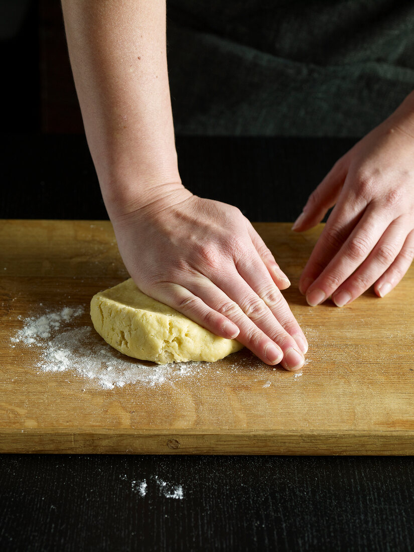 Close-up of hand Kneading dough on wooden board, step 1