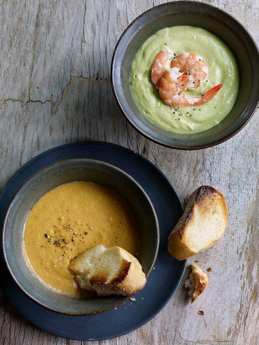 Gazpacho and avocado soup in bowls, overhead view