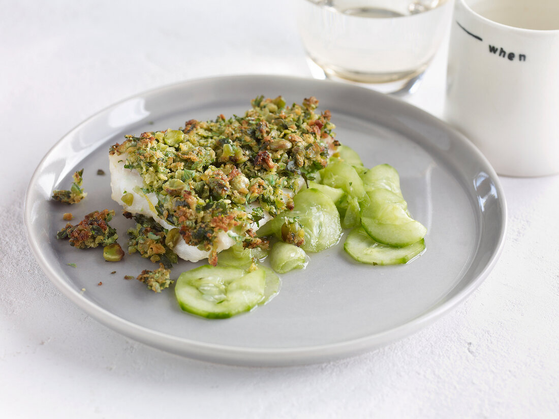 Fish fillet with wasabi crust and cucumber salad on plate