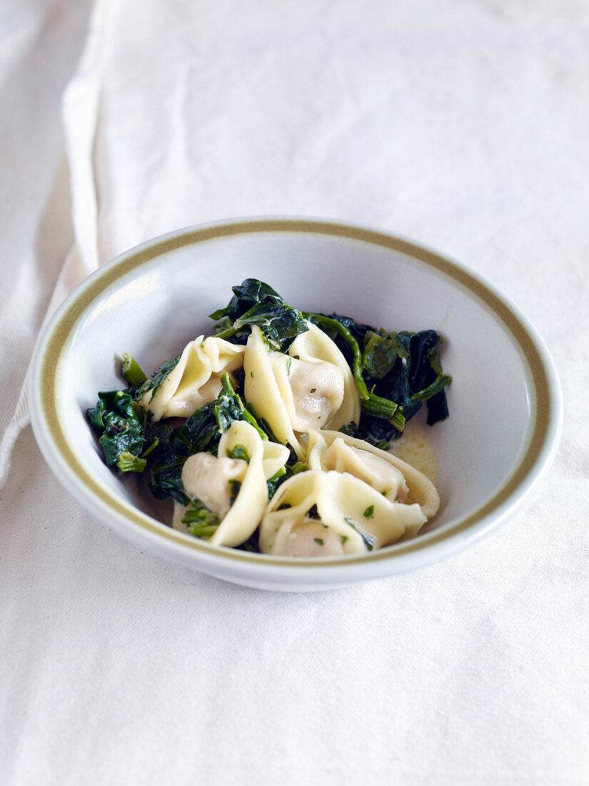 Tortellini with spinach in bowl