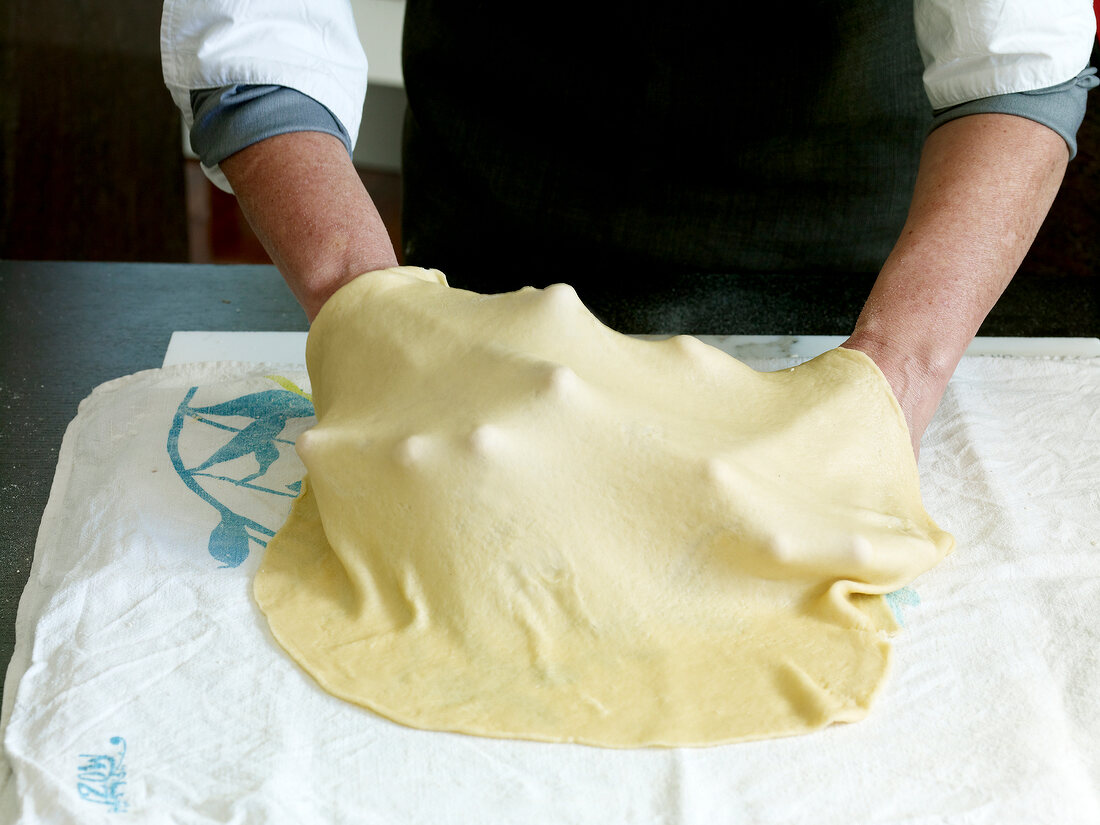 Close-up of hand spreading dough, step 2