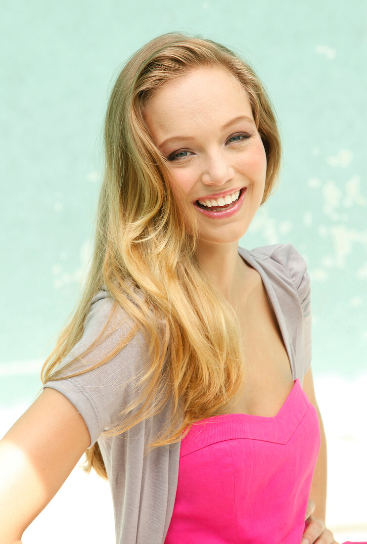 Portrait of beautiful blonde woman wearing pink and gray top, smiling