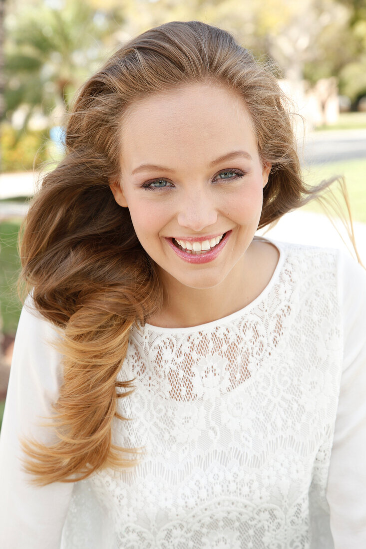 Portrait of pretty blonde woman wearing white lace top, smiling