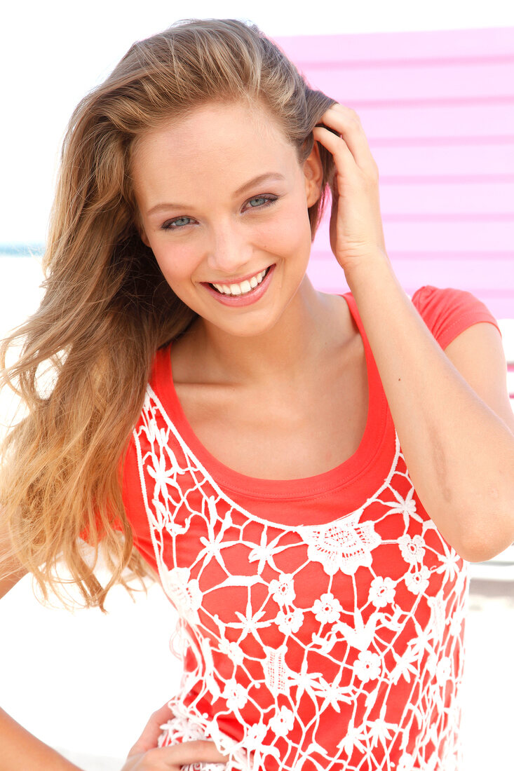 Portrait of pretty woman wearing orange-shirt and white fishnet top, smiling