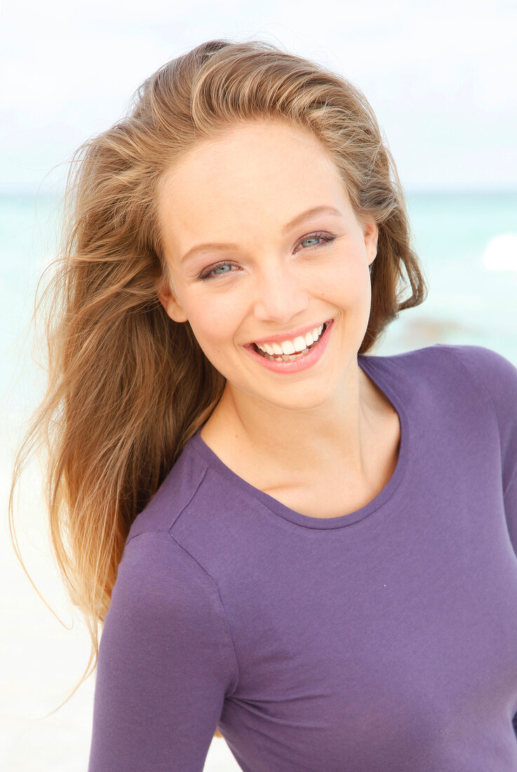 Portrait of beautiful blonde woman wearing purple top, smiling