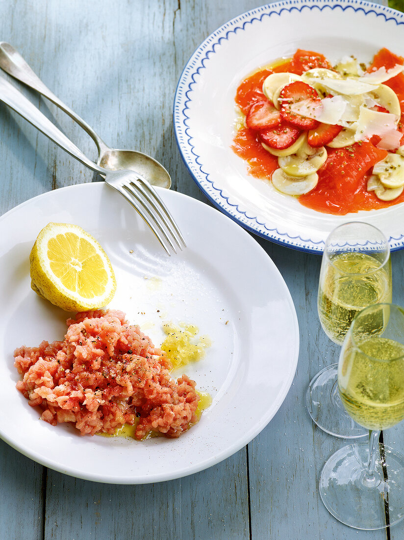 Smoked salmon with strawberries and veal tartare on plates and wine glasses