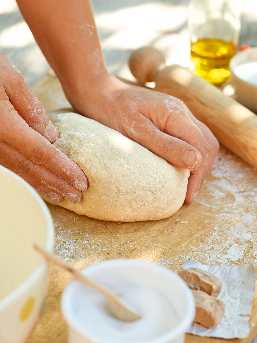 Close-up of hand kneading pizza dough