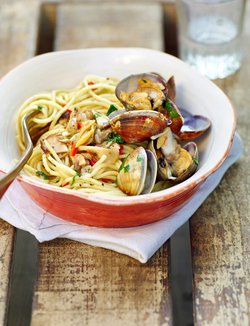 Spaghetti with clams and mushrooms in bowl during summer, Italy