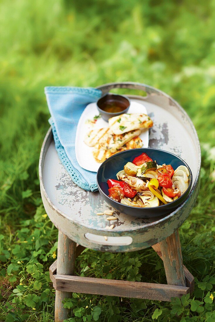 Oven-roasted vegetables and grilled halloumi on a table outside