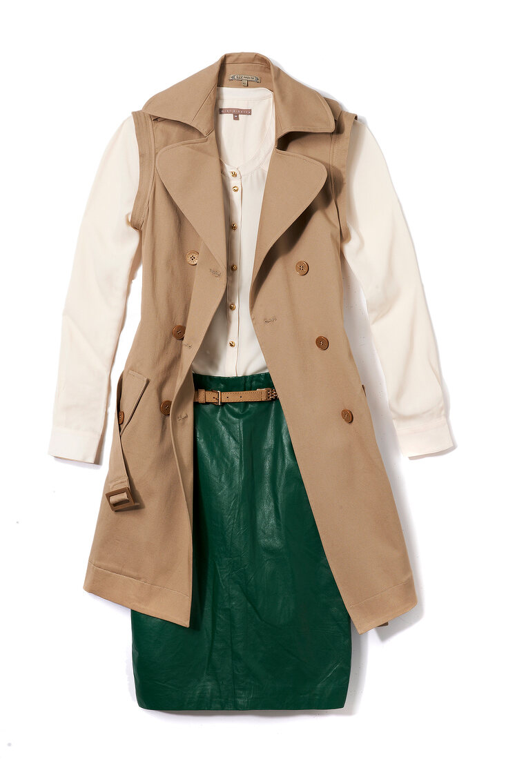 Beige trench with detachable sleeves and green leather skirt on white background