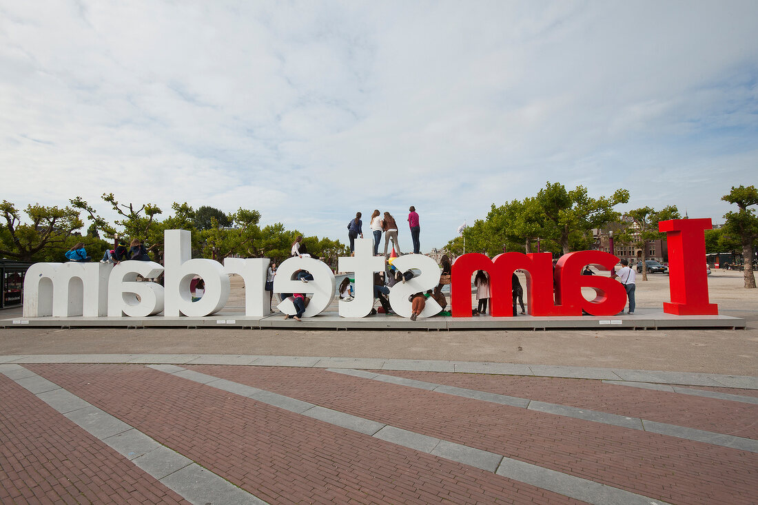 Tourists standing on lettering of I Amsterdam in Museumplein, Amsterdam, Netherlands