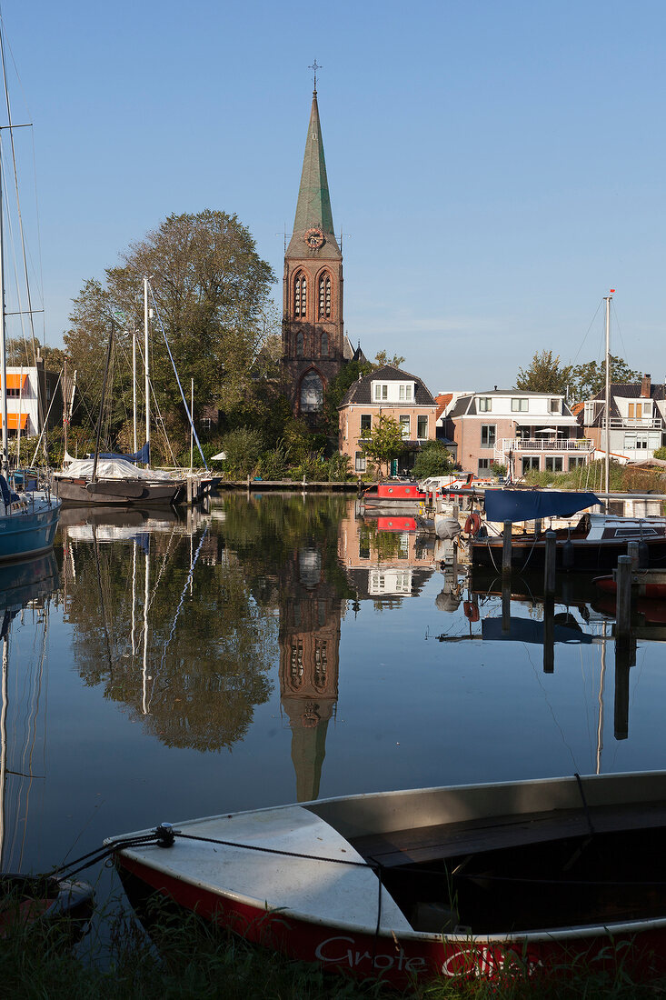 View of church and boats moored in IJ river, Schellingwoude, Amsterdam, Netherlands
