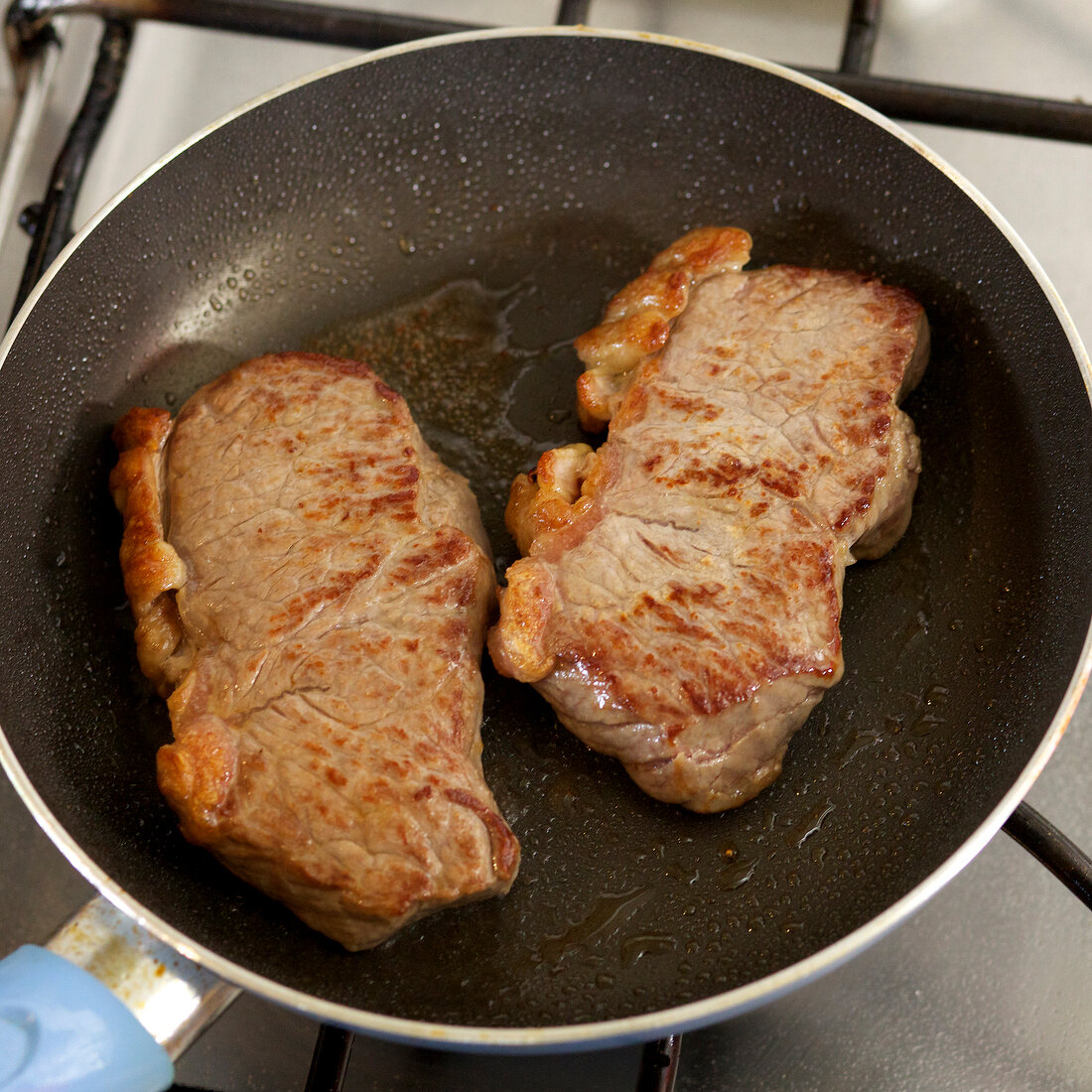 Close-up of steaks being fried in pan, step 3