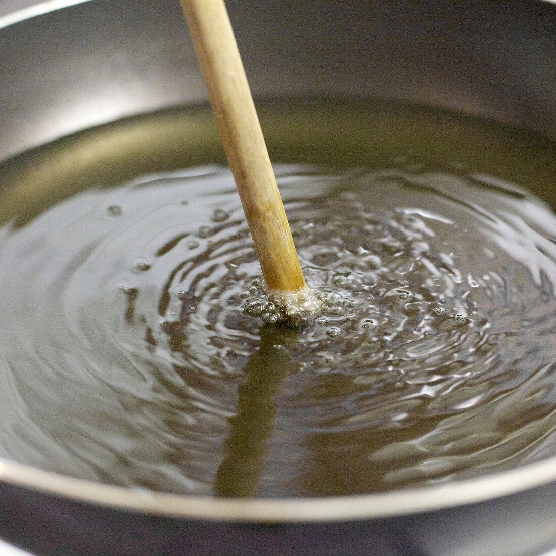 Close-up of wooden spoon dipped in oil to measure temperature, step 3