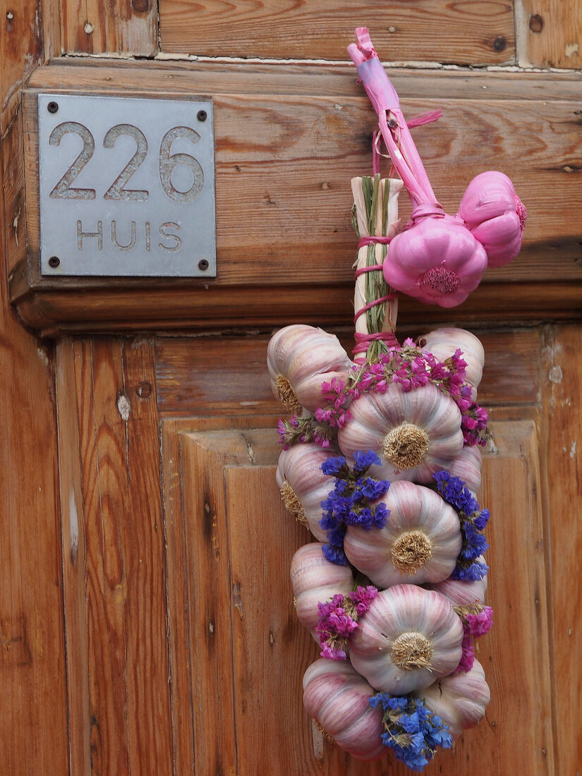Garlic bulbs tied and decorated with flowers hung on door, Gerard Doustraat 226, Amsterdam